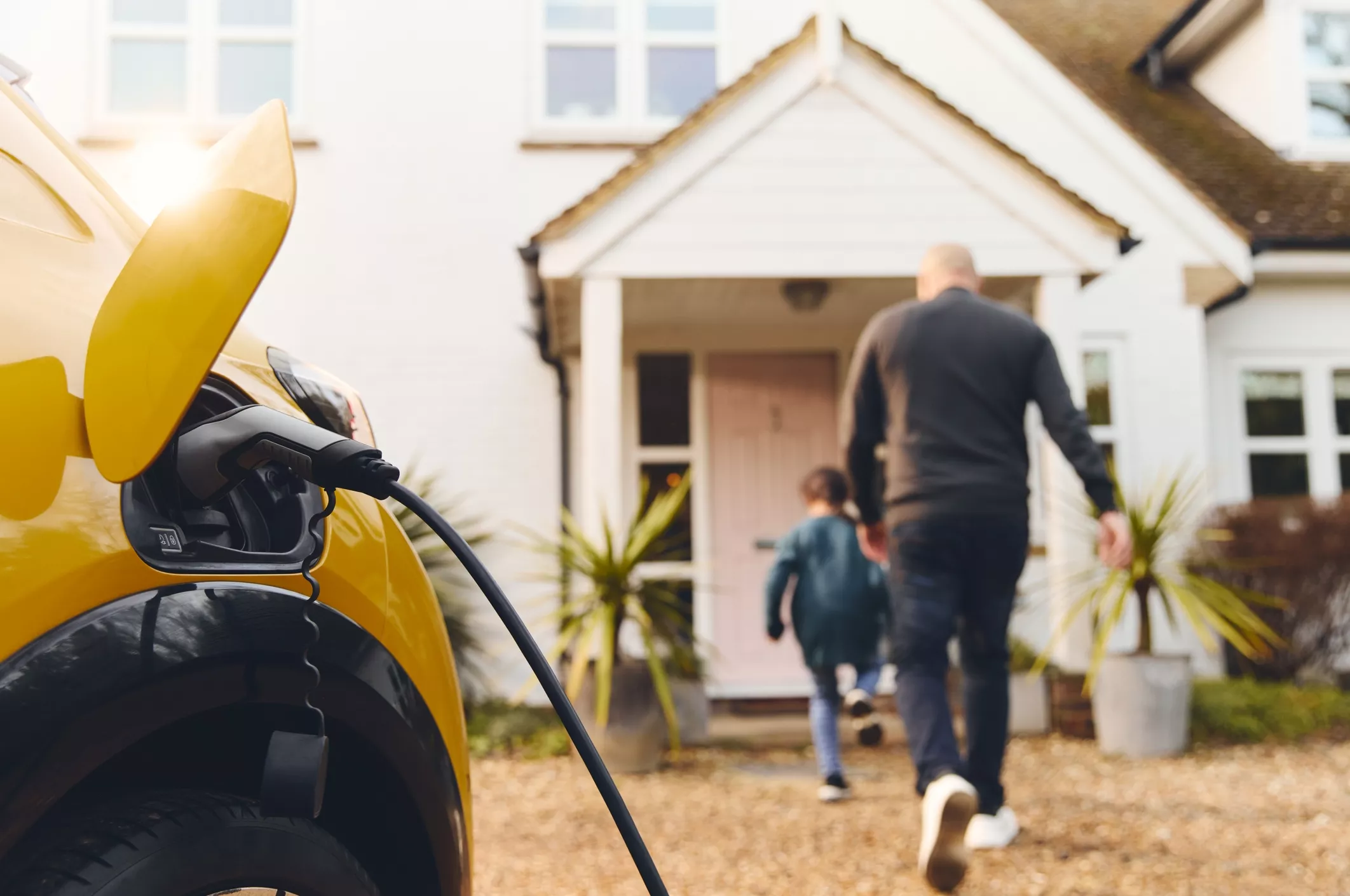 family walking to house with car on charge